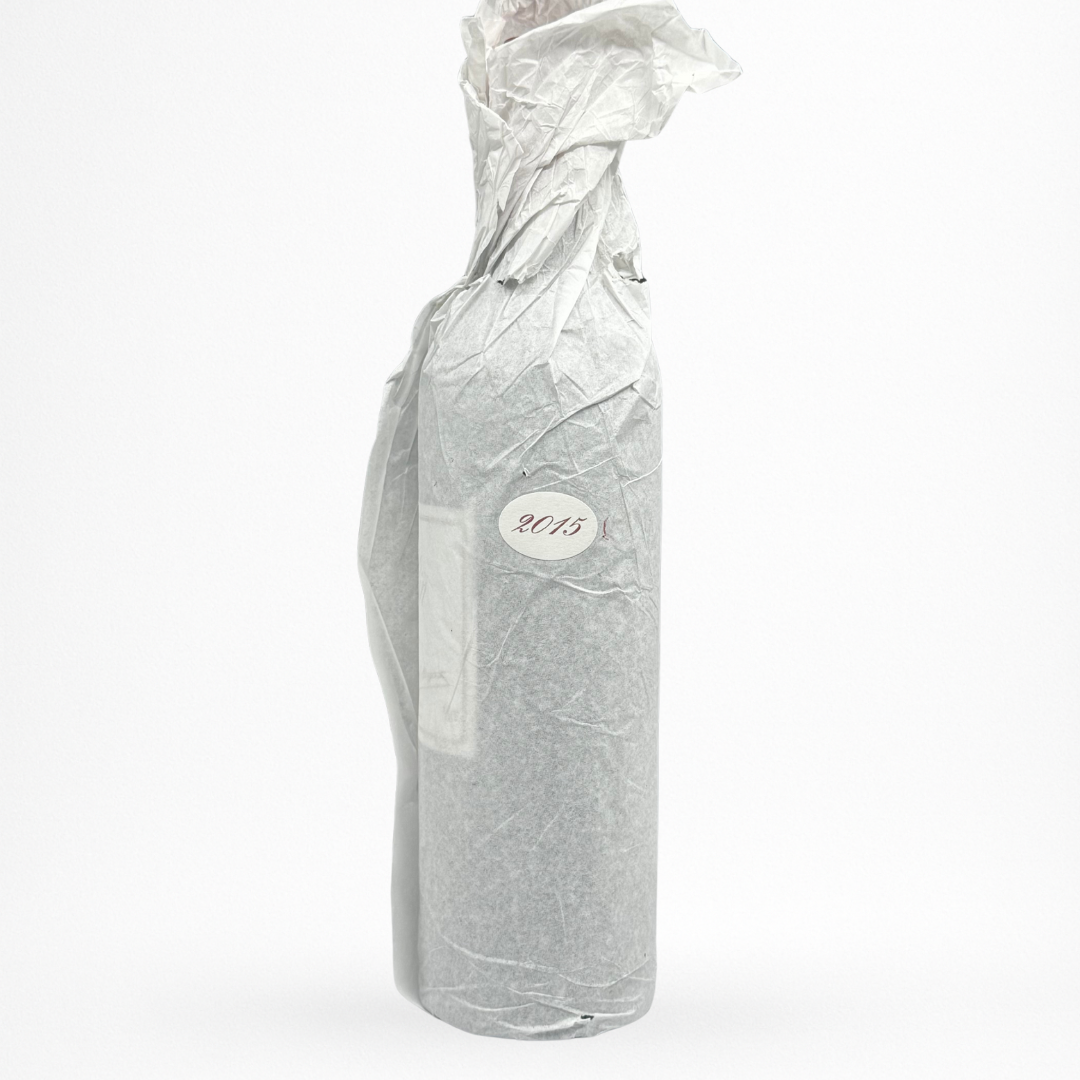 Château Le Pin 2015 – Pomerol, bouteille 75 cl emballée dans un papier de soie avec pastille “2015”, vue contre-étiquette sur fond blanc.