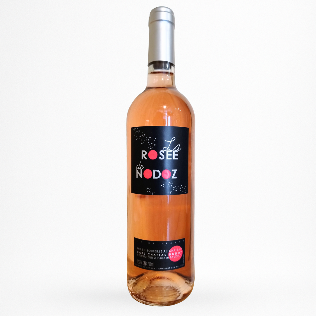 Bouteille de Château Nodoz – La Rosée de Nodoz Rosé 2023 (Vin de France) : bouteille transparente élancée, capsule argent, vin rosé saumoné. Étiquette principale noire avec texte “La ROSÉE de NODOZ” (avec pastilles roses/rouges dans les lettres) + petite contre-étiquette noire en bas.
